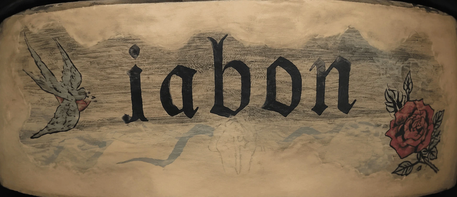 Hand-painted gothic 'Jabon' lettering on the barber chair — flanked by a swallow tattoo and a rose